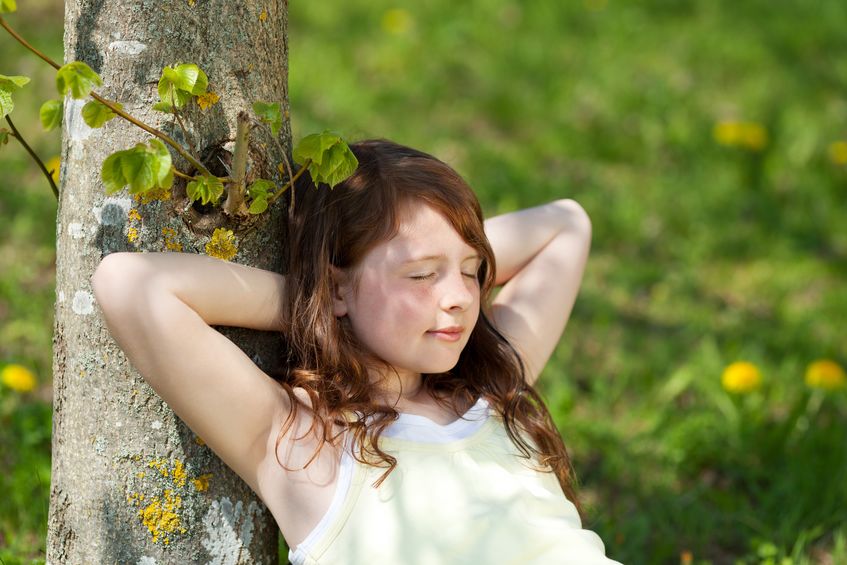 21203193 - young girl with eyes closed leaning on tree trunk in park